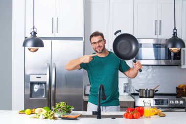 Adam mutfakta yemek pişiriyor. Aşçı şefi tencereli bir yemek hazırlıyor. Menü tarifi sağlıklı yemek. Adam modern mutfakta yemek pişiriyor. Olgun bir adam mutfakta yemek hazırlıyor.