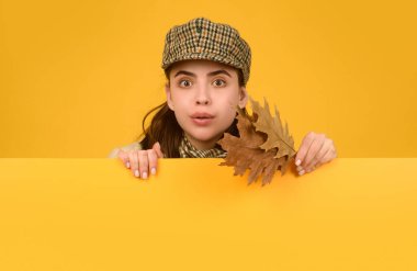 Sonbahar kadını, izole edilmiş stüdyo portresi. Sonbahar yaprakları olan komik bir genç kız. Sarı arka planda sonbahar şapkası ve atkısı olan güzel bir kız. Poster tahtası tasarımı