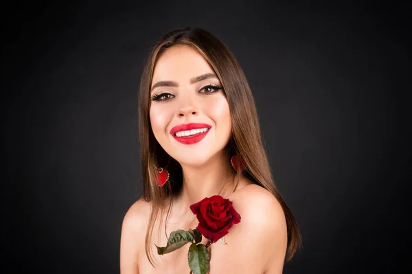 Beautiful woman with rose. Brunette girl with flower. Closeup face of young beautiful woman with a healthy clean skin. Pretty woman with bright makeup