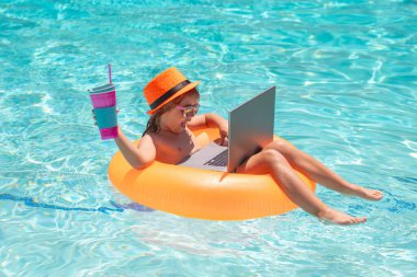Yaz havuzunda dizüstü bilgisayarda çalışan çocuk