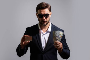 Gri banknotlar halinde nakit para tutan adam. Bir sürü banknotla birlikte iş adamının stüdyo portresi. Dolar parası konsepti. Kariyer zenginliği işi. Nakit dolar afişi