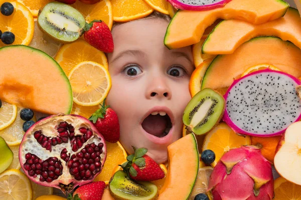 Vitamins from fruits. Mix of fruits near excited kids face. Assorted mix of summer fresh fruits. Healthy nutrition for kids