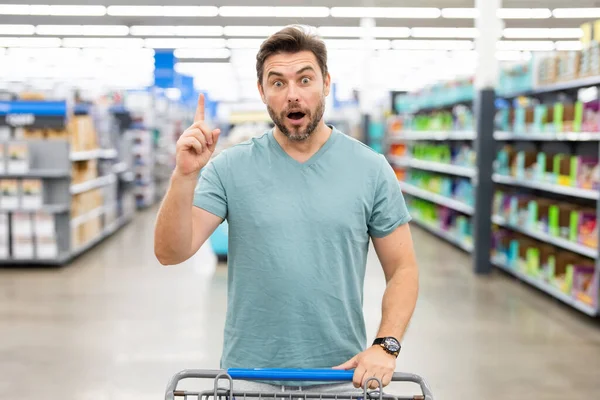 Man with shopping trolley. Middle aged millennial man in a food store. Supermarket shopping and grocery shop concept. Man man 40s with shopping cart