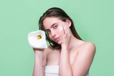 Stüdyo arka planına vücut kremi süren genç bir kadın. Güzellik rutini. Mükemmel bir teni ve çiçeği olan güzel bir kadının stüdyo yüzü. Kırışıklık kremi. Güzellik kavramı