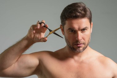 Beyaz, yakışıklı, kendine güvenen bir adam tek başına makasıyla saç kesmeye çalışıyor. Erkek tıraşı. Berber makası, berber dükkanı. Berber makası. Saç kesme konsepti. Erkek saç stili ve saç kesimi