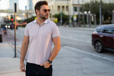 Büyük şehirde kendine güvenen yakışıklı bir adamın portresi. Sokakta poz veren sıradan giyinmiş seksi bir adam. Şehir yaşam tarzında başarılı bir erkek model. Kafkasyalı orta yaşlı adam dışarıda.