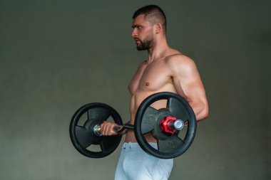 Muscular man lifting weights at gym. Handsome guy prepare to do exercises with dumbbell
