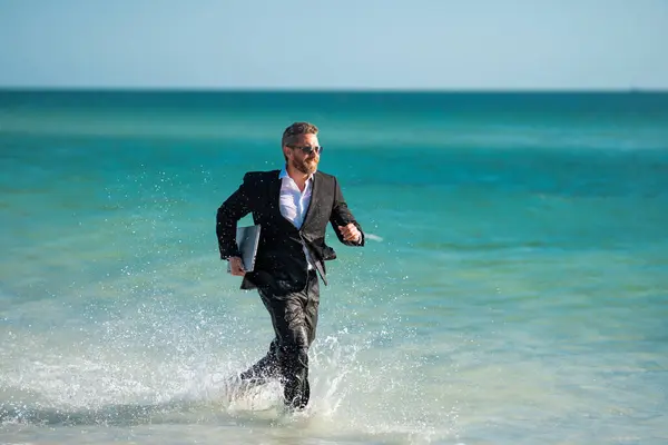 Funny business man in suit on sea. Summer vacation, business on sea beach. Summer rest, business people concept. Business man remote on-line working. Dream for summer vacations office workers