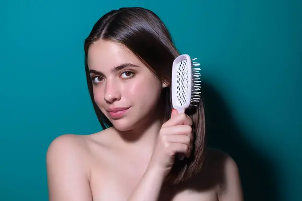 Woman combing her hair. Cares about a healthy and clean hair. Beauty hair salon concept. Girl with a comb in studio. Brushing hair, smooth soft silky hairs effect keratin. Hairs brush