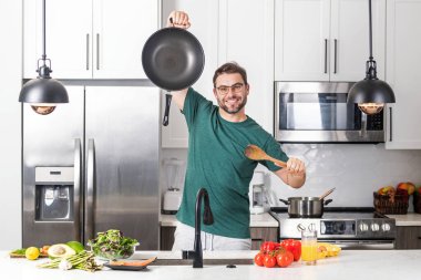 Evde yemek pişirmek. Mutfakta yemek hazırlayan adam. Erkek aşçı evde yemek hazırlıyor. Şef yemek yapıyor. Yemek pişiren adam, mutfak tenceresi, yemek tabağı. Adam mutfak içinde çorba hazırlıyor.