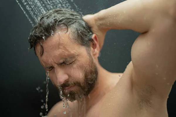 Middle aged man washing hair in bath. Guy bathing shower head in bathtub. Face in foam in shower. Bathing man taking shower. Close up guy showering. Shower concept. Man is under water drops in showers