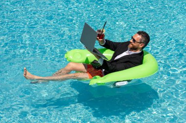 Komik bir serbest yazar, uzaktan kumandalı internet işi, elektronik çalışma. Yaz eğlencesi. Takım elbiseli bir iş adamı su havuzunda dizüstü bilgisayarla çalışıyor. İş adamı yaz havuzunda dizüstü bilgisayarda çalışıyor.