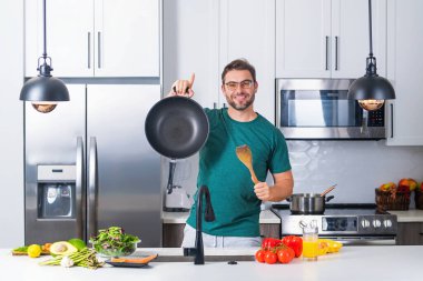 Adam mutfakta yemek pişiriyor. Şef aşçı tencereli bir yemek hazırlıyor. Menü tarifi sağlıklı yemek. Evde yemek pişiren adam mutfakta yemek hazırlıyor. Olgun bir adam mutfakta yemek hazırlıyor.