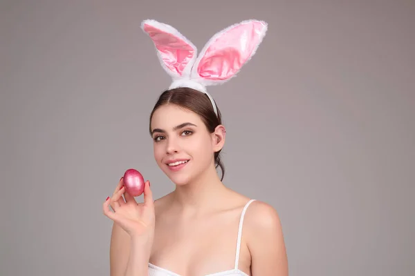 Easter girl. Young woman with bunny ears and Easter eggs on studio background. Festive bunny and easter eggs season. Stylish woman in Easter bunny ears isolated on studio background