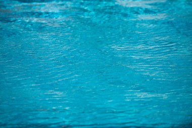 Su arka planı, dalgalanma dalgaları. Mavi yüzme havuzu deseni. Deniz yüzeyi. Yüzme havuzunda su ve güneş yansıması. Kopyalama alanı olan pankart