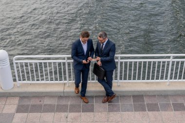 Anlaşma öneriyor, yeni projeyi tartışıyoruz. İş iletişimi. İki iş adamı dışarıda konuşuyor. İş arkadaşları projeyi tartışıyor ve düşünüyor. İki iş adamı arasında yürüyüp konuşuyoruz.