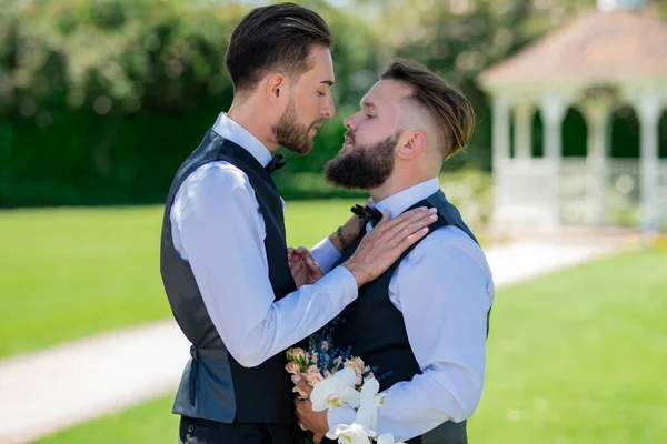 Gay man groom at wedding. Happy male gay couple with flowers holding hands on wedding. Romantic and sensual gay couple. Gay grooms together on Wedding day