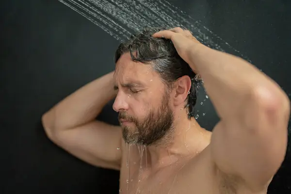 Man washing hair, close up portrait. Man bathing shower washing hair head in bathroom. Male model washing hair in shower. Sexy man taking shower. Guy showering. Male shampoo and washing hair concept