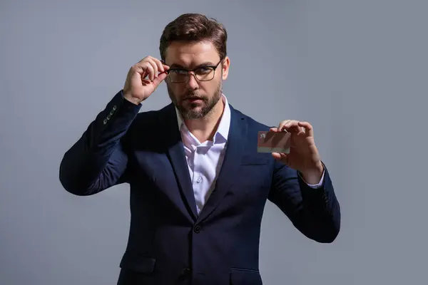 Business man holding credit card over isolated studio gray background. Businessman with credit bank card, recommend bank discounts. Credit card for e-banking, e-commerce, cashback transaction