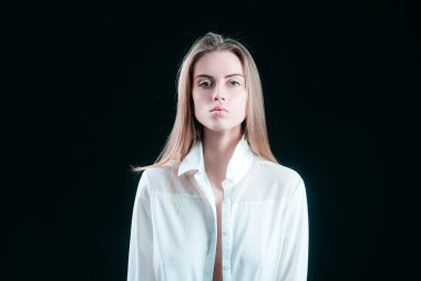 Siyah arka planda poz veren gömlekli zarif genç bir bayan. Işık ve gölge. Güzel bir kadının portresi.