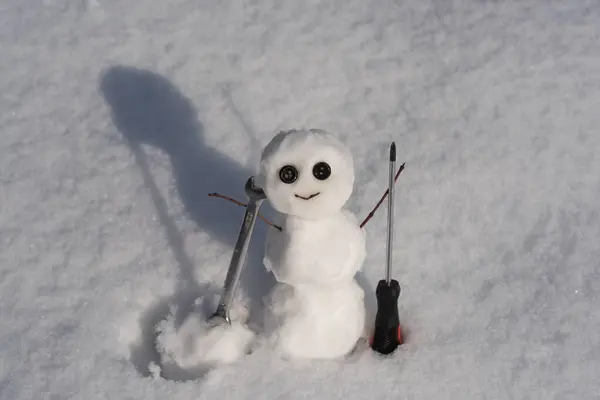 Snow man. Funny snowman on snowy field. The morning before Christmas. Repairman with wrench and screwdriver. Support repair and recover service