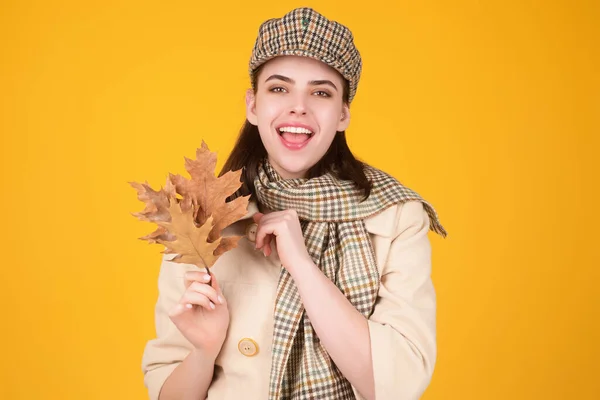Autumn portrait woman with fall maple leaves on studio isolated background with copy space. Autumn portrait of cheerful woman with fall leaves wearing beret hat and autumn warm scarf