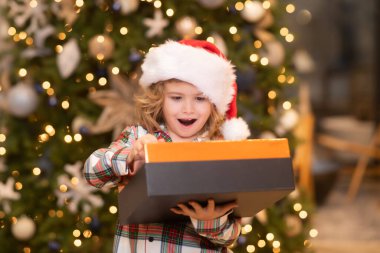 Sürpriz çocuk Noel hediyelerini açıyor. Noel 'de evde bir çocuk. Noel 'i ya da yeni yılı kutlayan küçük bir çocuk. Kapalı portre, komik çocuk yüzü.