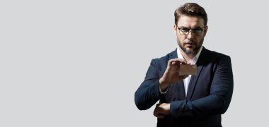 Gri arka planda kredi kartı olan bir adamın stüdyo portresi. Para yönetimi ve kredi puanı. Ödül programları. Kredi limiti. Başlık için afiş, kopyalama alanı. Web tasarımı için poster