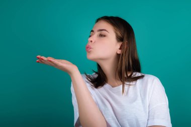 Dudaklarını üfleyerek tatlı bir öpücük yolluyor. Stüdyonun arka planında izole edilmiş dudak bükerek öpücük gönderen güzel kız. Şefkat duyguları. Portre güzel kadın hava öpücüğü yolluyor. Öpücük. Öpülmüş kız