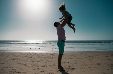 Baba oğlunu mavi gökyüzüne fırlattı. Babası çocuğu fırlatıyor. Yakışıklı adam baba, küçük oğlan çocuğu taşıyor. Mutlu baba kucağında çocuğu. Yaşam tarzı ve aile tatili, mutluluk adamı konsepti.