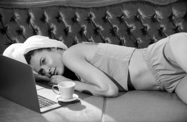 Beyaz bornozlu, yatak odasında laptoplu ve kahveli genç ve güzel kadınlar. Evde ya da otel odasında yatakta tasasız kadın modeller. Sabah serinliği