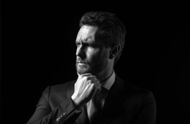 Siyah arka planda duran izole iş adamının portresi. Olgun iş adamı düşünür, yakından bakar.