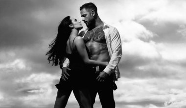 Moda aşıkları öpüşüyor ve sarılıyor. Romantik çift randevusu. Birbirine aşık bir çift. Atletik tişörtsüz, kaslı bir adam öpüşüyor ve romantik bir kadını kucaklıyor. Hassas tutkuda seksi, zarif bir çift.