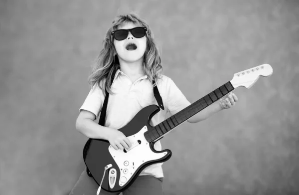 Rock and roll, little kid rock star. Little boy playing guitar outdoor. Music for children