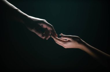 Two hands reaching toward. Tenderness, tendet touch hands in black background. Romantic touch with fingers, love. Hand creation of adam