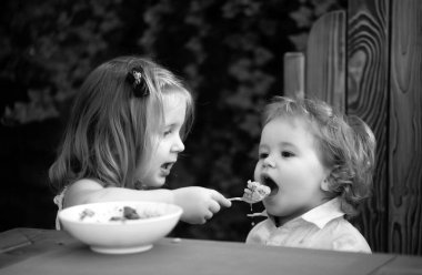 Sevimli bebek yemek yer, bebekler yer. Küçük kız kardeş bebeği besliyor.