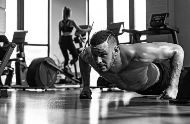 Şınav çeken formda bir adam, şınav çeken bir adam. Gövdesi kaslı, tişörtsüz bir adam spor salonunda.