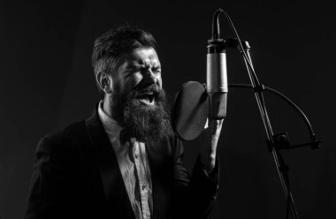 Şarkıcı kayıt stüdyosunda mikrofonla şarkı söylüyor.