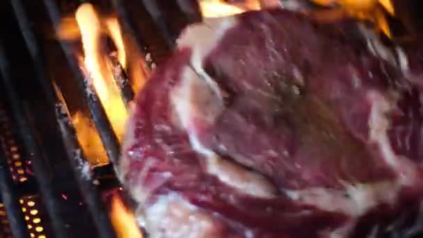 グリルのバーベキュー肉 グリルのバーベキューで炎で調理するために用意された生のステーキ肉牛 鉄製キャストグレートのビーフステーキ バーベキューグリルで焼いた肉 ローストビーフステーキ — ストック動画