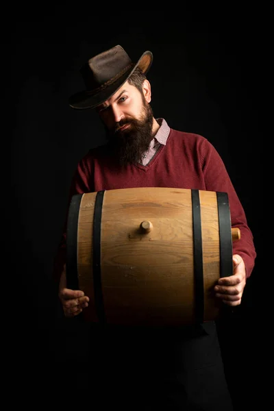 Man hold wooden barrel on black. Oktoberfest. Bearded brewer man. Serious man with wooden barrel. Brewery concept. Beer for pub and bar. Oak barrels, keg. Man carries wooden barrel. Barrel with wine