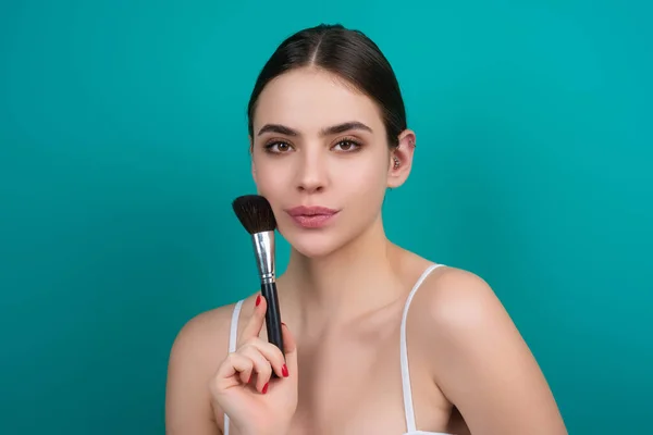 Woman apply powder on face. Beauty Makeup. Portrait of female model with cosmetic brush. Perfect soft skin and natural makeup. Applying powder blush highlighter, foundation tone