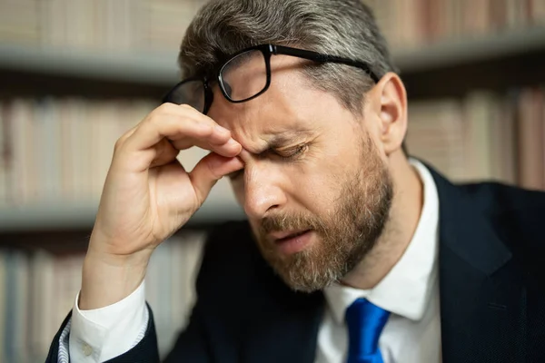 Close up face of stressed man with headache migraine. Headache, tiredness and stress. Man in suit uses a laptop, is tired got headache migraine. Headache pain concept