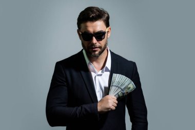 Başarılı bir iş adamı para sayıyor. Yakışıklı orta yaşlı adam 100 dolarlık banknotları tutuyor. Elinde para tutan adam. Kâr ve finansal başarı. Dolar nakiti olan zengin bir adam.