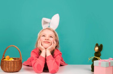 Easter child. Funny girl wearing bunny ears and having fun with Easter eggs. Funny bunny kids, copy space