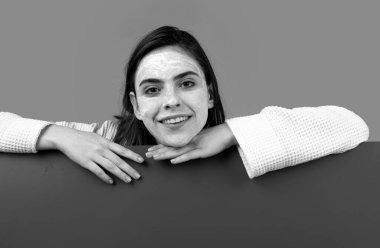 Kozmetik yüz prosedürü olan güzel bir kadın, kaplıca derisi konsepti. Mesaj için fotokopi alanı olan spa kızı. Ürün teklif etmek. Reklam için jestler. Mavi arkaplan