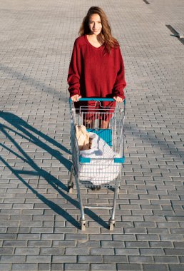 Tüketim, satış ve indirim. Dışarıda alışveriş arabası olan mutlu kadın.