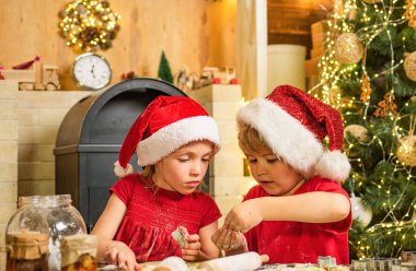 Noel Baba şapkalı şirin çocuklar aile için tatil yemeği hazırlıyorlar. Noel Baba aşçısı Noel arifesinde Noel Baba 'ya teşekkür etmek için kurabiye. Minnettar bir erkek ya da kıza hediye bıraktığı için.