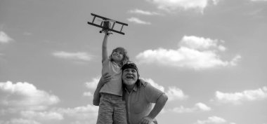 Mavi gökyüzü ve bulutların arkasında oyuncak uçakları olan torun çocuk ve büyükbaba. İki erkek, büyükbaba ve torunu dışarıda oynuyorlar. Nesil ailesi