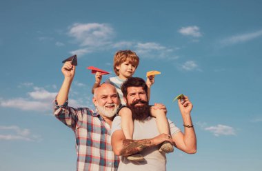 Üç erkek nesli. Babasıyla dışarıda oynayan sevimli bir oğlu var. Babalar Günü - Büyükbaba, baba ve oğul kucaklaşıyor ve birlikte eğleniyorlar.