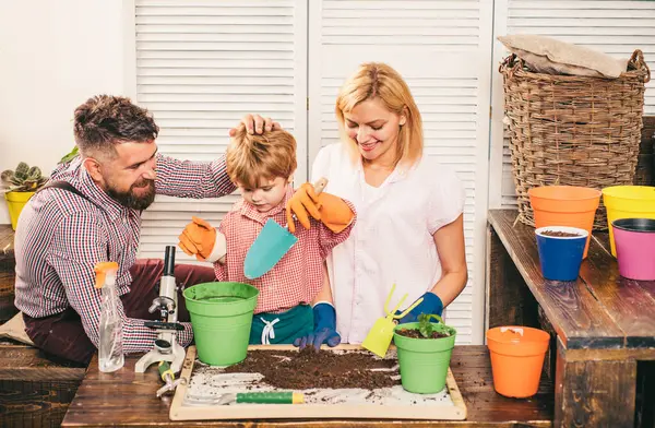 Happy family planting sprout in a plant pot. Mother father and child son growing plant in pot. Family Weekend. Portrair of cheerful parents and their little child